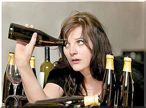 The girl peeks into the bottle - alcoholism