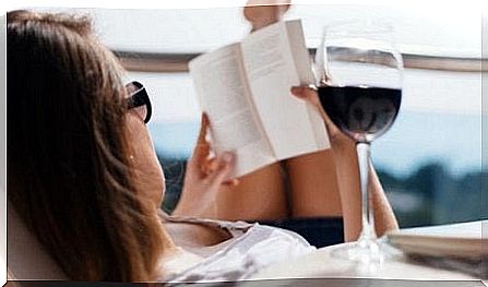 A woman is reading a book while having a glass of wine