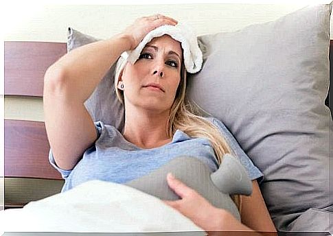 The woman is lying in bed with a compress on her head